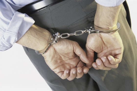 Close-up of a businessman with his hands handcuffed behind his back